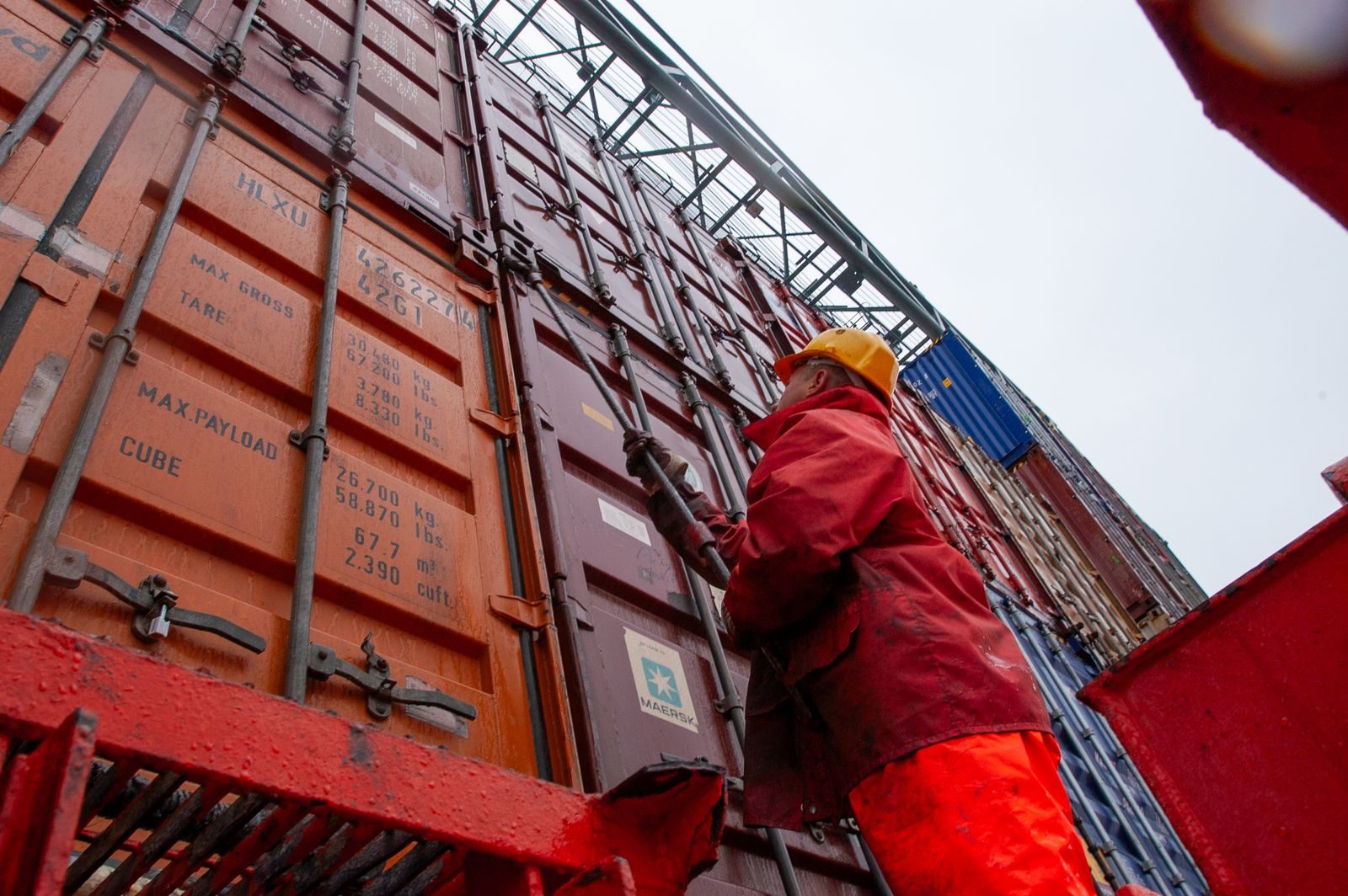 Containers stacked at a port terminal, being inspected.